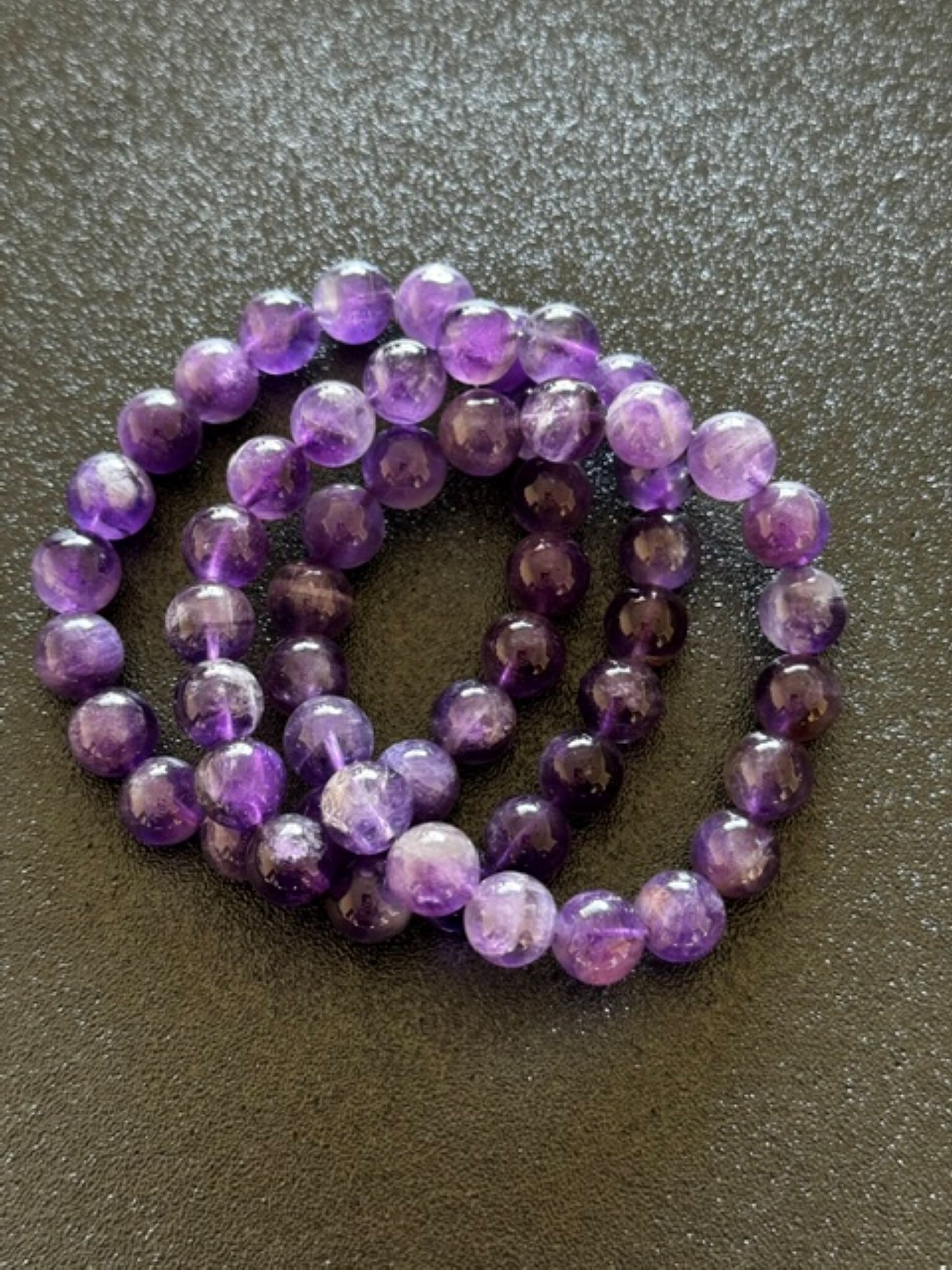 Amethyst beaded crystal bracelet made of polished purple beads strung on an elastic or cord band, often worn as a calming accessory associated with relaxation and mindfulness.