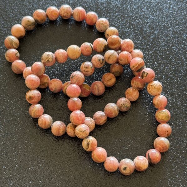 Pink rhodochrosite crystal with natural swirling patterns and soft rosy tones, often associated with emotional healing, comfort, and self-love.
