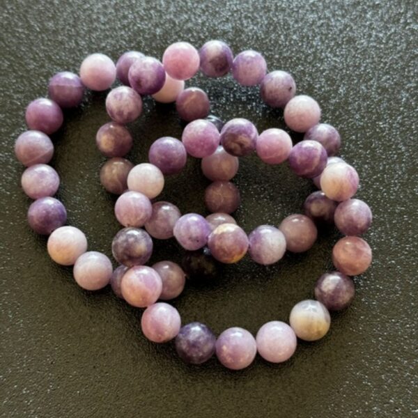 Soft purple lepidolite crystal sitting on a surface, symbolising calmness and emotional balance, often associated with stress relief and mindful relaxation.