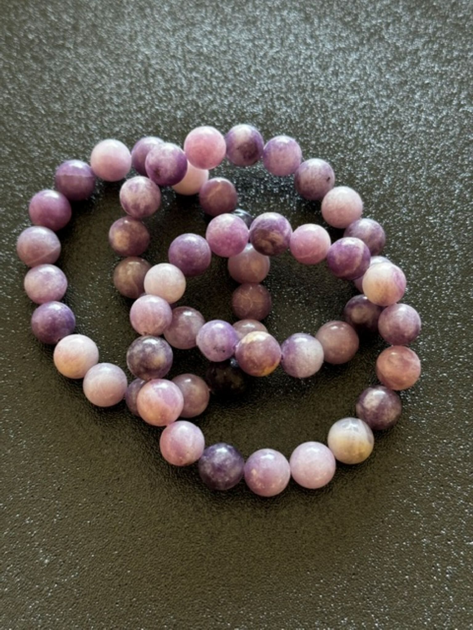 Soft purple lepidolite crystal sitting on a surface, symbolising calmness and emotional balance, often associated with stress relief and mindful relaxation.