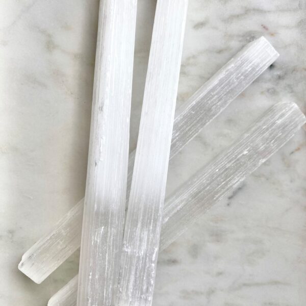 a group of white selenite sticks on a marble surface.
